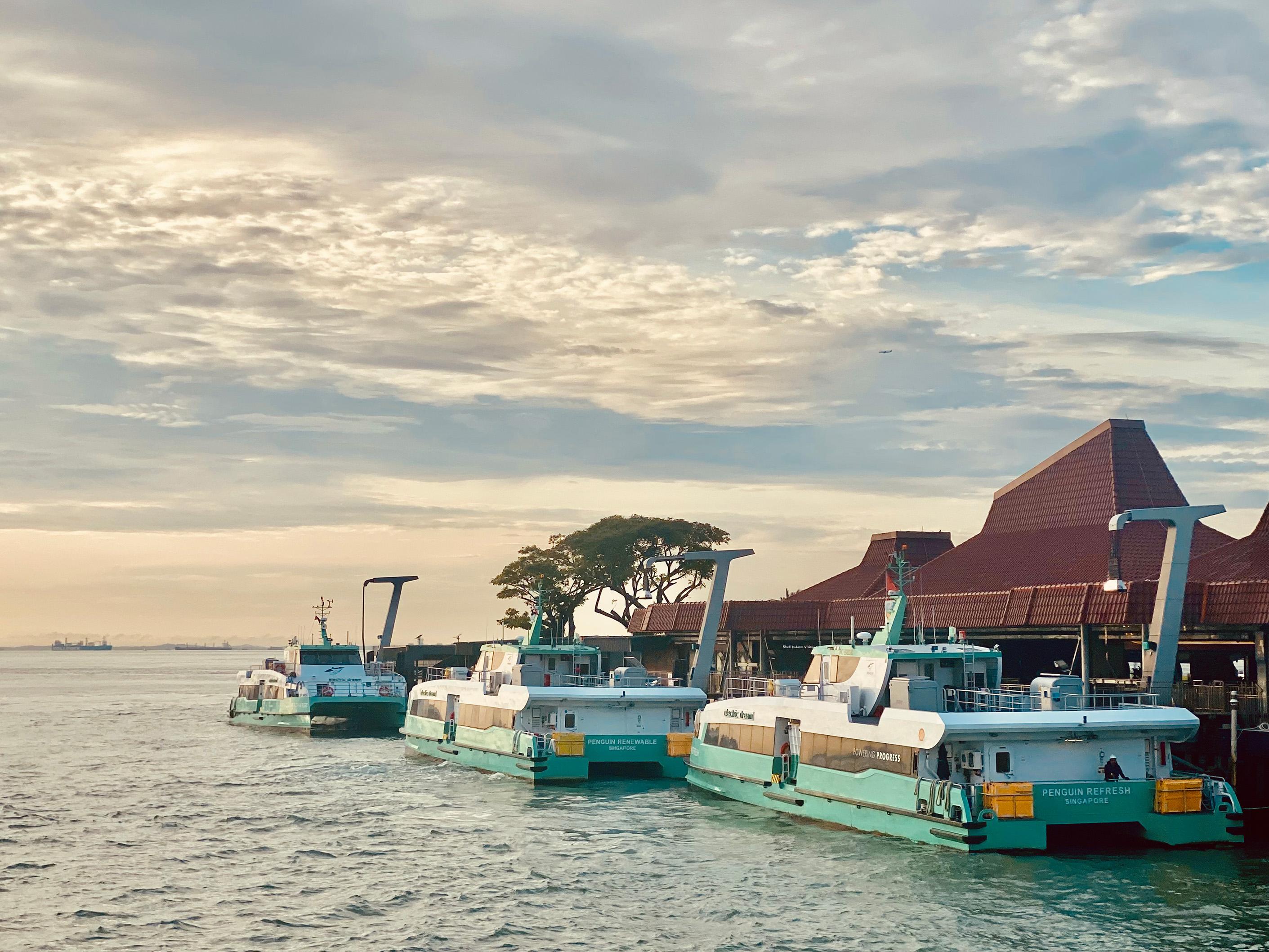 3 ferries parked at a small harbour, looking out towards the sea