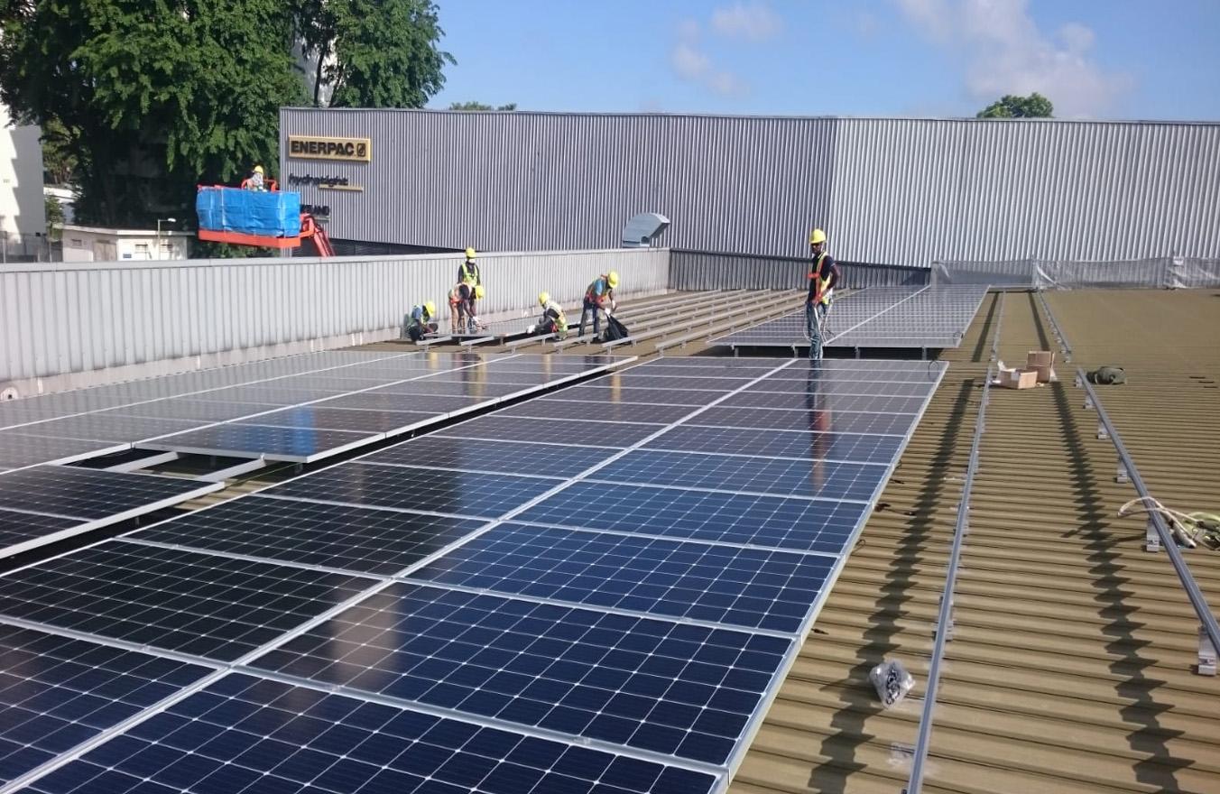 a few construction workers fixing solar panels on a roof